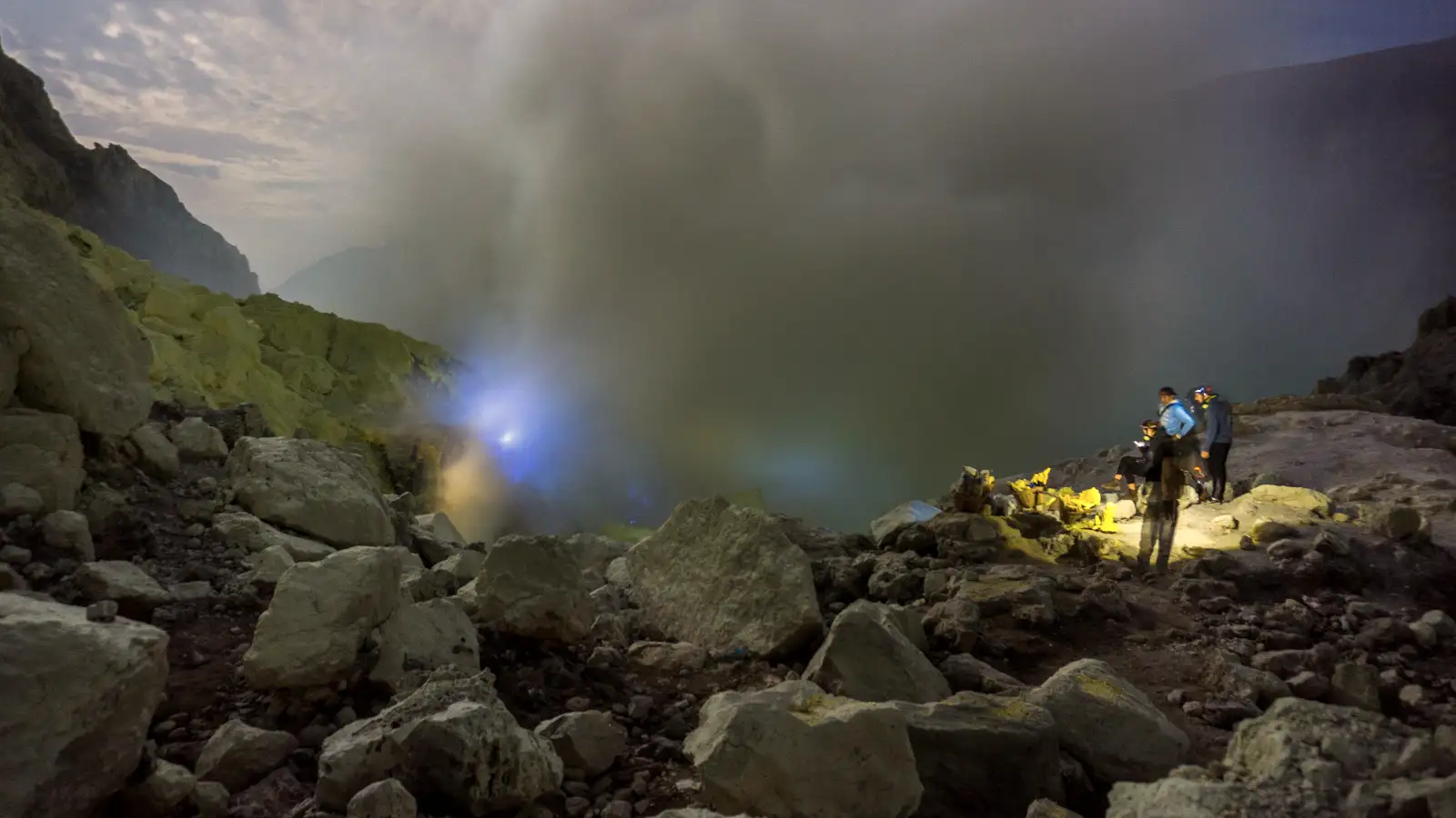 Ijen Crater turquoise acid lake and sulfur smoke during sunrise