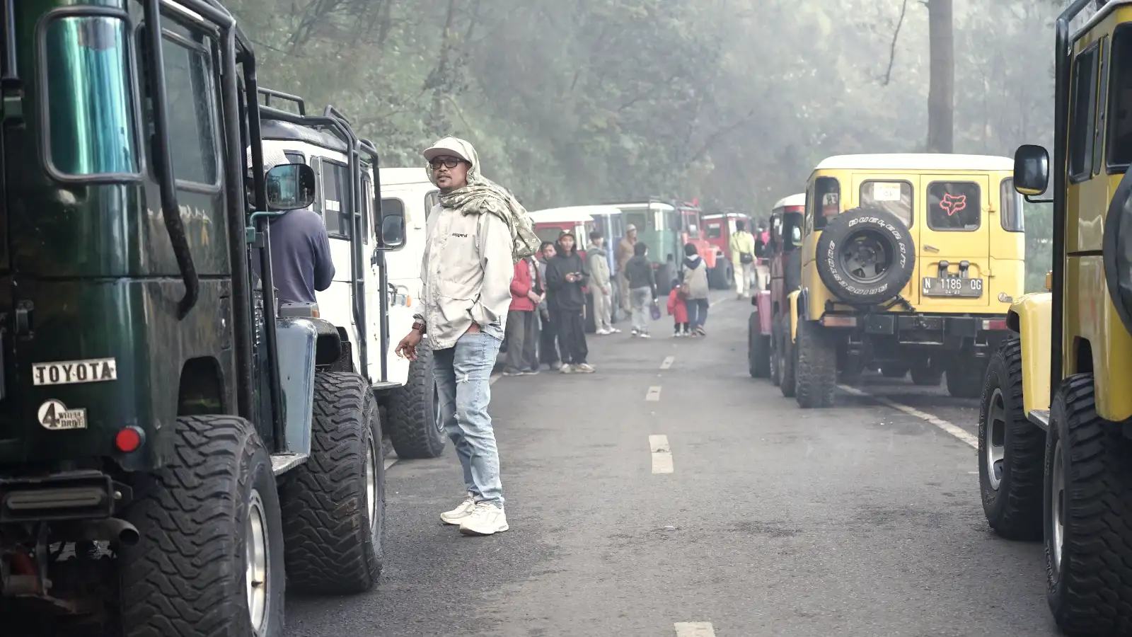 Group of colorful jeeps driving through the Sea of Sand toward Mount Bromo crater